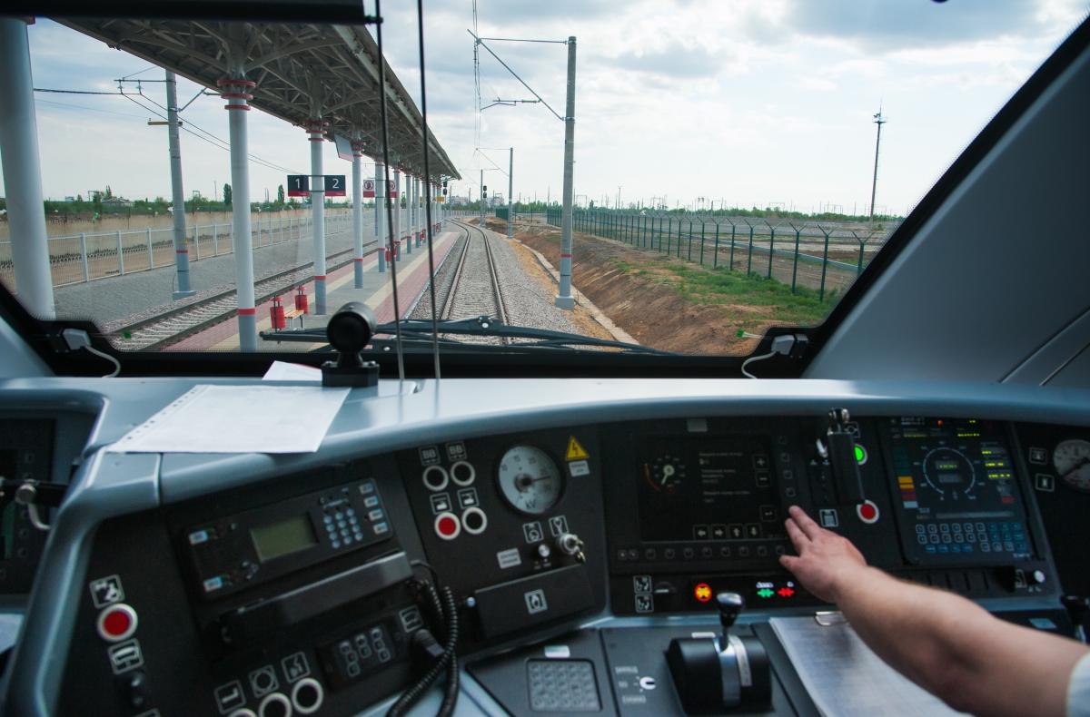 control panel of a train with a hand leaning forward to press a button