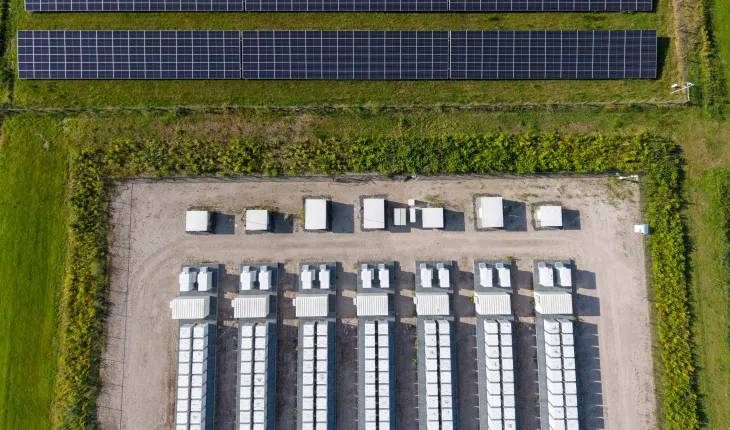 Aerial view of a large-scale solar farm featuring extensive rows of photovoltaic panels and a battery energy storage system in the rural landscape of Wanneperveen