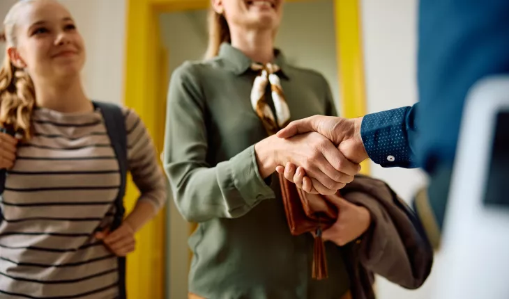 Two parents shaking the hand of a teacher