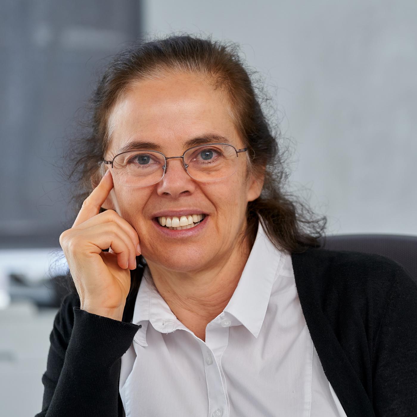 A smiling woman wearing glasses and a collared shirt